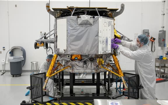 Un miembro del equipo Astrobotic de la NASA coloca una pegatina de la NASA en el módulo de aterrizaje lunar de Astrobotic Peregrine el 14 de noviembre, en las Instalaciones de Operaciones Espaciales Astrobotic en Florida.