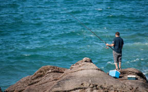 Man rock fishing at base of Mount Maunganui.