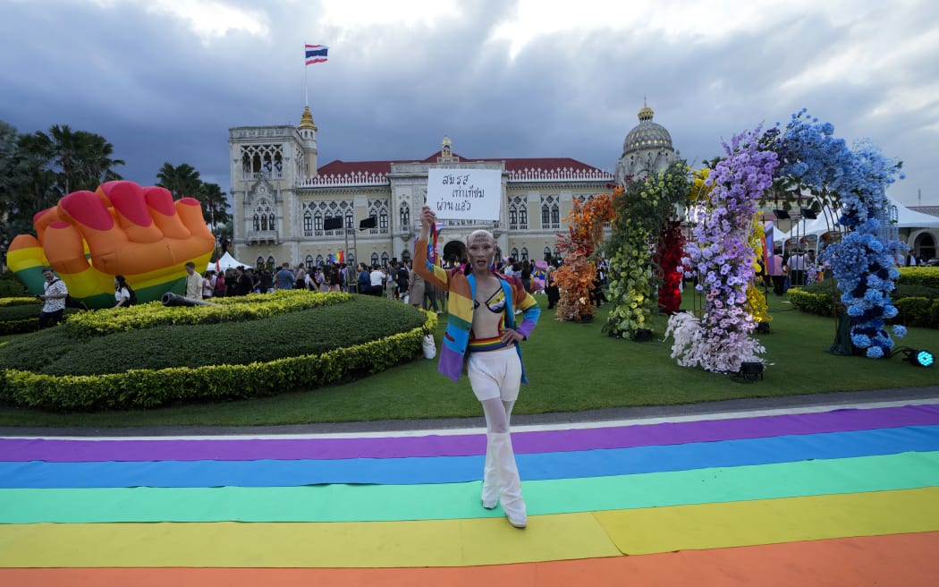 A supporter celebrates after Thailand’s Senate overwhelmingly approved a landmark bill to legalize same-sex marriages in Bangkok, Thailand, Tuesday, June 18, 2024. Banner reads, "Marriage equality law was passed by Senate". (AP Photo/Sakchai Lalit)
