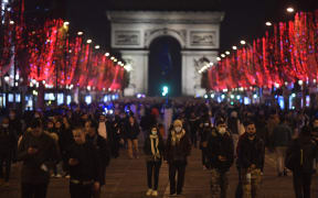 Masked pedestrians walk along the Champs-Elysees Avenue in Paris, France on New Year's Eve, 31 December 2021.