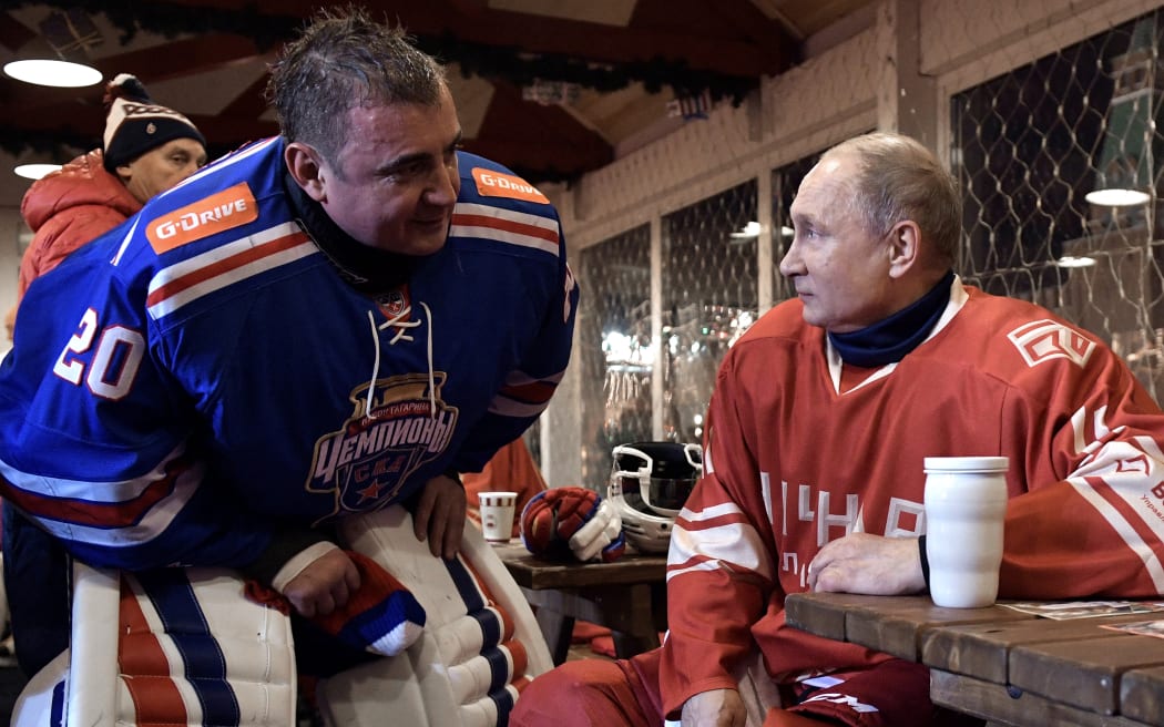 Russian President Vladimir Putin (R) speaks with Governor of the Tula Region Alexei Dyumin (L) during a ten minutes' break during the Night Hockey League match at the GUM department store skating rink at Red Square in Moscow on December 22, 2017.