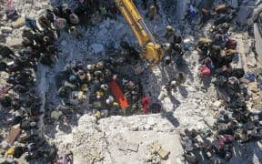 An aerial picture shows rescuers searching the rubble of buildings for casualties and survivors in the village of Salqin in Syria's Idlib province following an earthquake, on February 7, 2023.