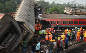 Rescue workers gather around damaged carriages at the accident site of a three-train collision near Balasore, about 200 km (125 miles) from the state capital Bhubaneswar in the eastern state of Odisha, on June 3, 2023. At least 288 people were killed and more than 850 injured in a horrific three-train collision in India, officials said on June 3, the country's deadliest rail accident in more than 20 years. (Photo by DIBYANGSHU SARKAR / AFP)