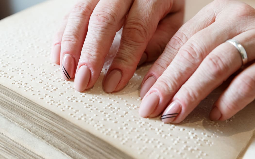 close up view of woman reading braille text on old book