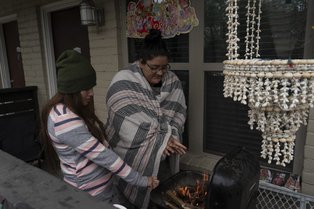 Karla Perez and Esperanza Gonzalez warm up by a barbecue grill during power outage caused by the winter storm on 16 February 2021 in Houston, Texas.