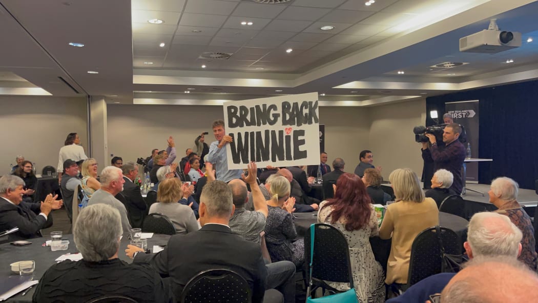 A person in the crowd puts up a poster in support of New Zealand First leader Winston Peters at the party's AGM on 20 June, 2021.