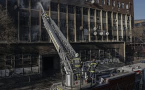 Firefighters extinguish a fire in a building in Johannesburg on 31 August, 2023. At least 20 people have died and more than 40 were injured in a fire that engulfed a five-storey building in central Johannesburg on August 31, 2023, the South African city's emergency services said.