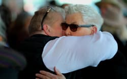Guests arrive at the memorial for Dame Jools Topp. Her sister, Lynda Topp is embraced.