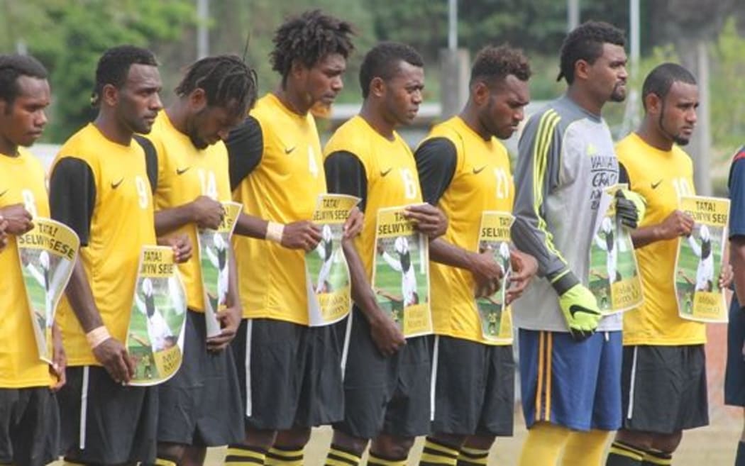Vanuatu players hold signs honouring former international Selwyn Sese before their match against Fiji.