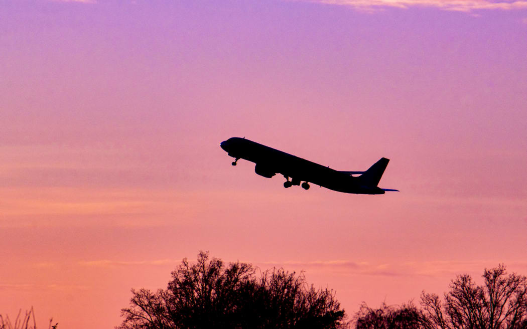Aircraft silhouette, a symbol illustration photo during the magic hour. Dusk and sunset golden hour with a colorful cloudy sky in Eindhoven. Images of a dark shape Airbus A320 aircraft departing and flying in the colorful European skyscape. The aviation industry and passenger traffic are phasing a difficult period with the Covid-19 coronavirus pandemic having a negative impact on the aviation and travel business industry with fears of a deteriorating situation due to the new Omega variant mutation. Eindhoven, the Netherlands on February 7, 2022 (Photo by Nicolas Economou/NurPhoto) (Photo by Nicolas Economou / NurPhoto via AFP)
