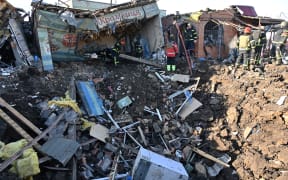 Ukrainian rescuers work on the site following a Russian missile strike on a local market in Shevchenkove village, Kharkiv region on January 9, 2023, amid the Russian invasion of Ukraine. - Oleg Sinegubov, head of the Kharkiv Regional State Administration in his Telegram channel said - according to the updated data of the Regional Center of Emergency Medical Assistance, as a result of an attack by the occupiers on Shevchenkove village, two people were killed. Women in their 50s and 60s. Another 5 people were injured. Among them is a child. (Photo by SERGEY BOBOK / AFP)
