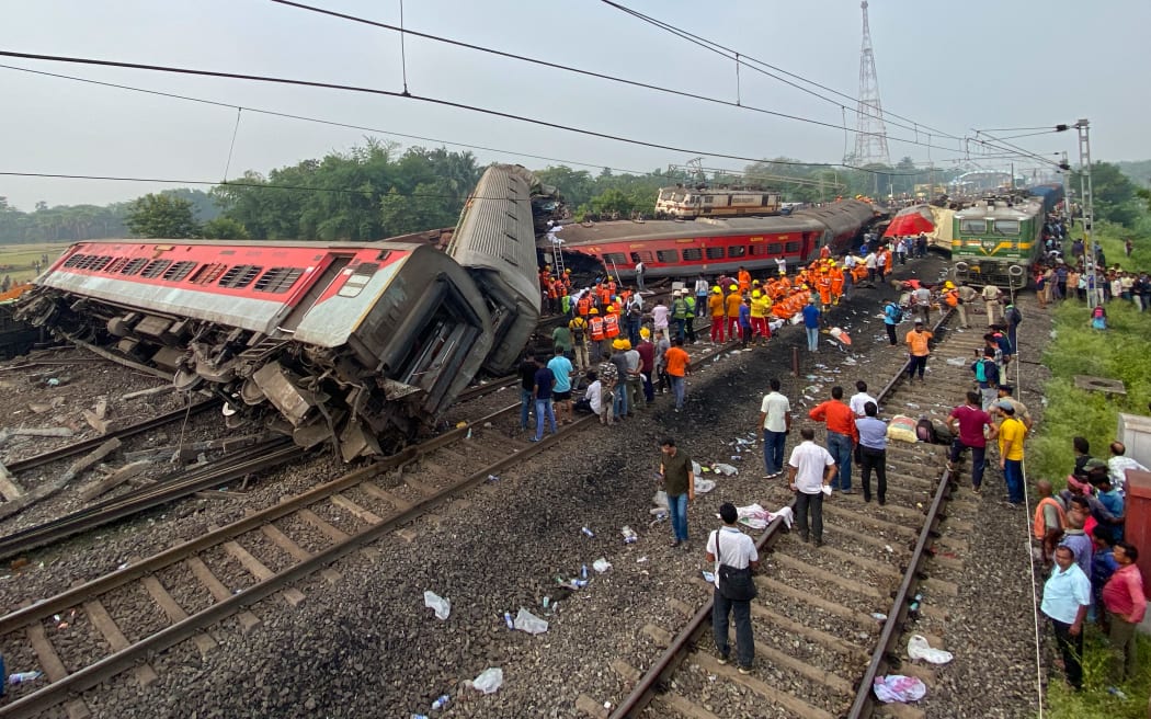 People gather at the accident site of a three-train collision near Balasore, about 200 km (125 miles) from the state capital Bhubaneswar, on June 3, 2023. At least 207 people were killed, more than 850 more were injured and many others are feared trapped after a horrific three-train collision late June 2 in eastern India's Odisha state, local officials said. (Photo by Dibyangshu SARKAR / AFP)