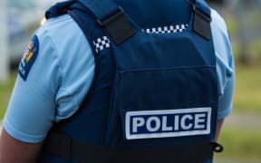 Close up of the back of a police officer wearing a vest.