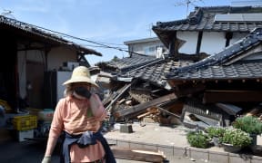 A woman stands in front of her damaged house in Mashiki, Kumamoto prefecture after a 6.5 magnitude quake struck the southwestern island of Kyushu on April 14.