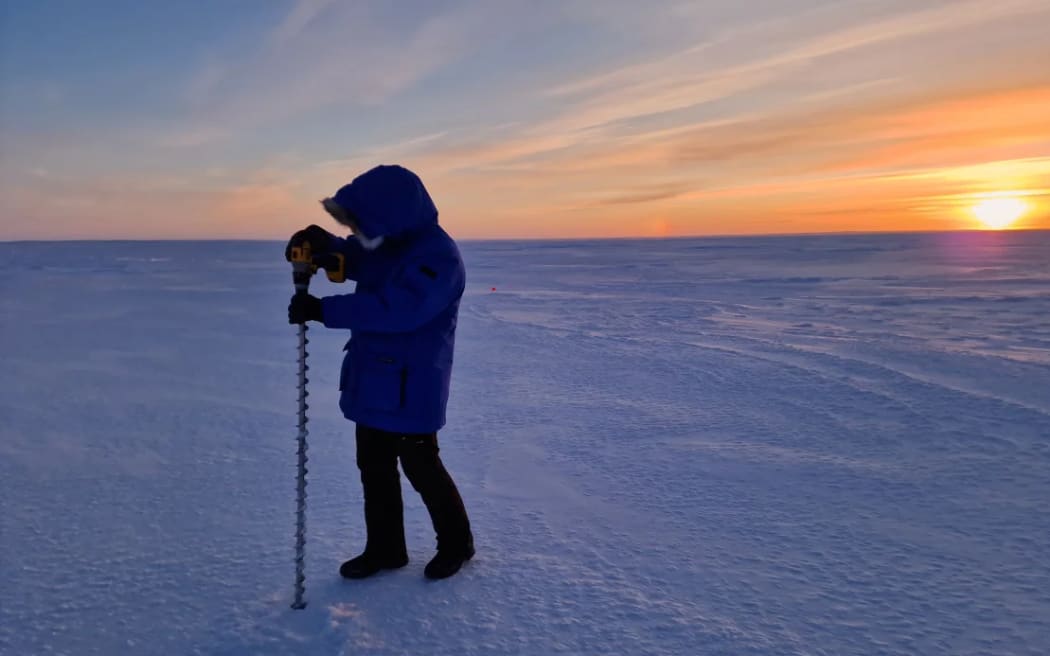 A member of the Real Ice team takes measurements on the sea ice in Cambridge Bay in January 2024.