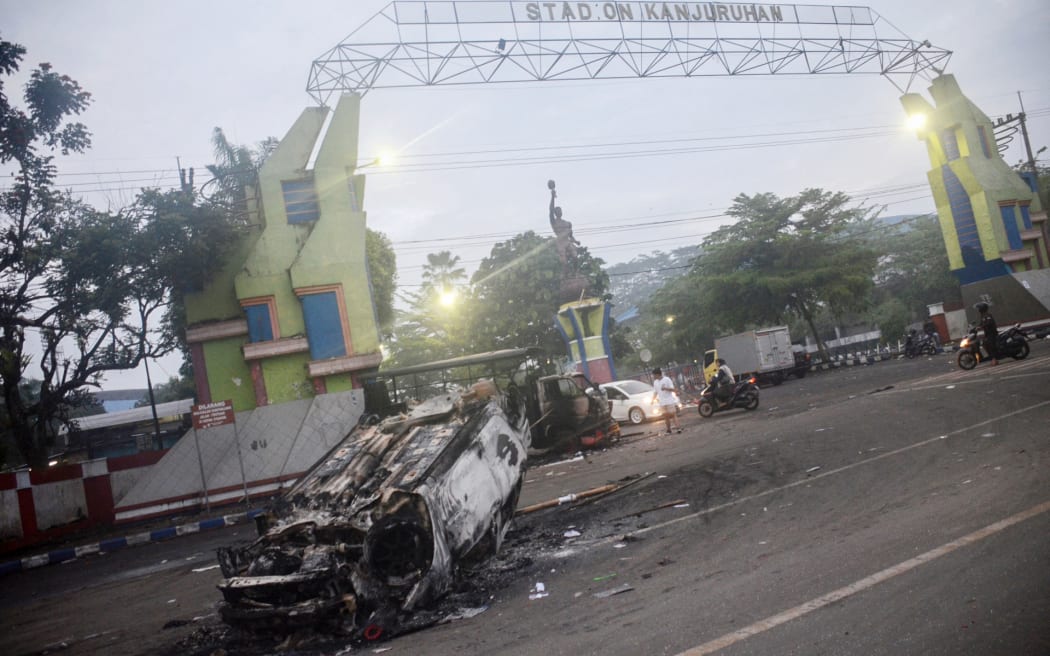 This picture shows a torched car outside Kanjuruhan stadium in Malang, East Java on October 2, 2022. - At least 127 people were killed when angry fans invaded a football pitch after a match between Arema FC and Persebaya Surabaya in Malang, East Java in Indonesia late on October 1, police said. (Photo by PUTRI / AFP)