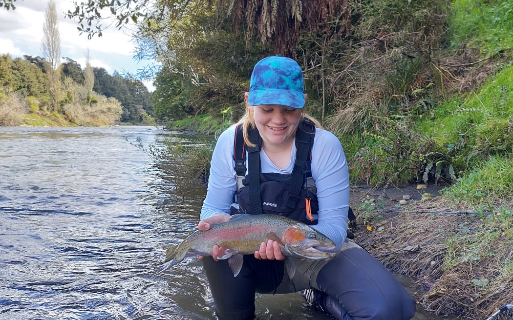 Fish and Game ranger Adam Daniel's daughter enjoying the trout caught in Whanganui River.