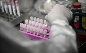 A laboratory technician wearing protective equipment works on the genome sequencing of the SARS-CoV-2 virus (Covid-19) and its variants at the Centre National de Reference of respiratory infections viruses of the Pasteur Institute in Paris on January 21, 2021.