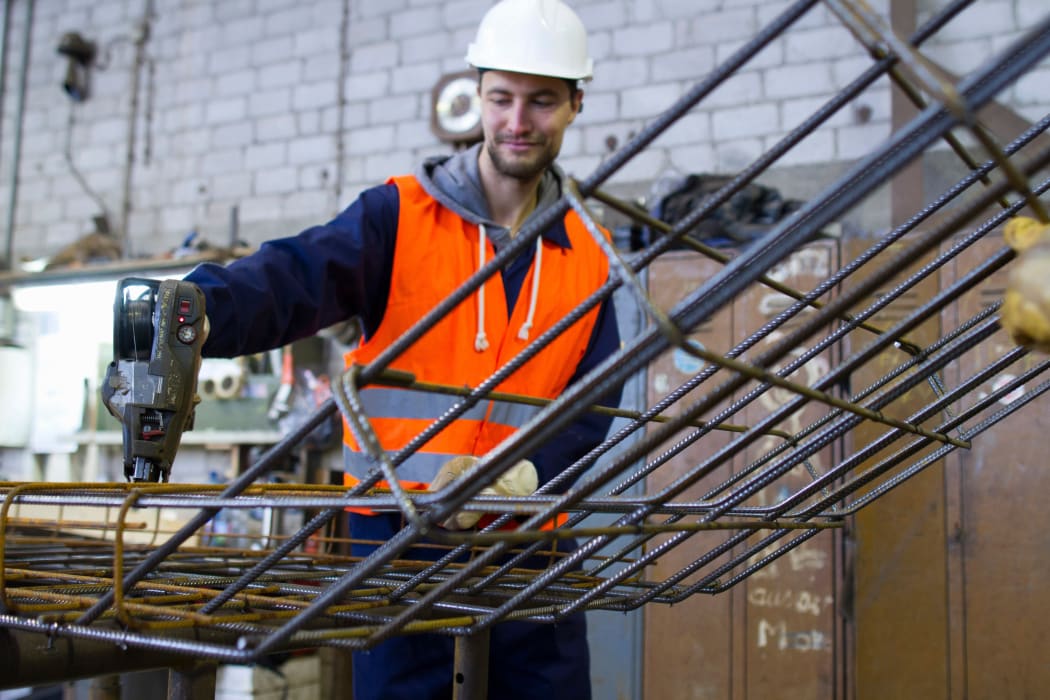 A factory worker attaches steel mesh at a concrete reinforcement factory.