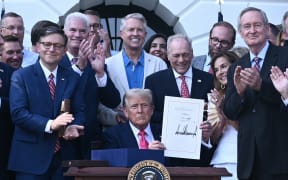 US President Donald Trump (C) shows his signature on the "Big Beautiful Bill Act" at the White House in Washington, DC, on July 4, 2025. US President Donald Trump signed his flagship tax and spending bill on July 4 in a pomp-laden Independence Day ceremony featuring fireworks and a flypast by the type of stealth bomber that bombed Iran. Trump pushed Republican lawmakers to get his unpopular "One Big Beautiful Bill" through a reluctant Congress in time for him to sign it into law on the US national holiday -- and they did so with a day to spare Thursday.