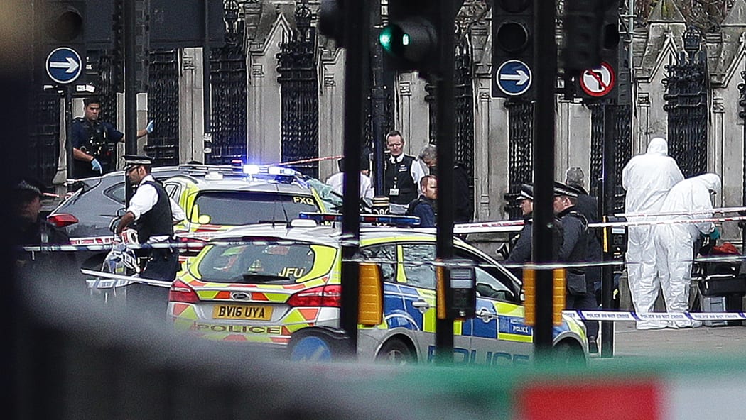 Armed police and forensic officers near a vehicle that crashed into the railings outside the House of Commons in central London.