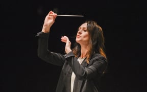 Natalie Murray Beale conducting. The baton is raised in her right hand above her head.