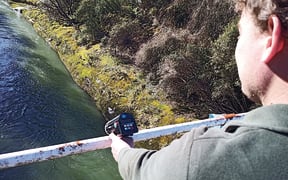 Regional council hydrology staff undertaking water monitoring with one of the new water radar guns.