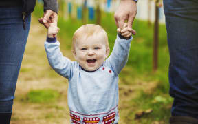 [England] Two adults and a baby boy holding hands in a polytunnel at a fruit farm. (Photo by Mint Images / Mint Images / Mint Images via AFP)