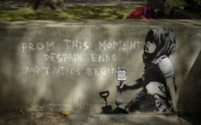 Dappled shade from a tree is cast over a new piece of street art that  is believed to be by street artist Banksy on a wall where Extinction Rebellion climate protesters had set up a camp in Marble Arch, London, Friday, April 26, 2019.