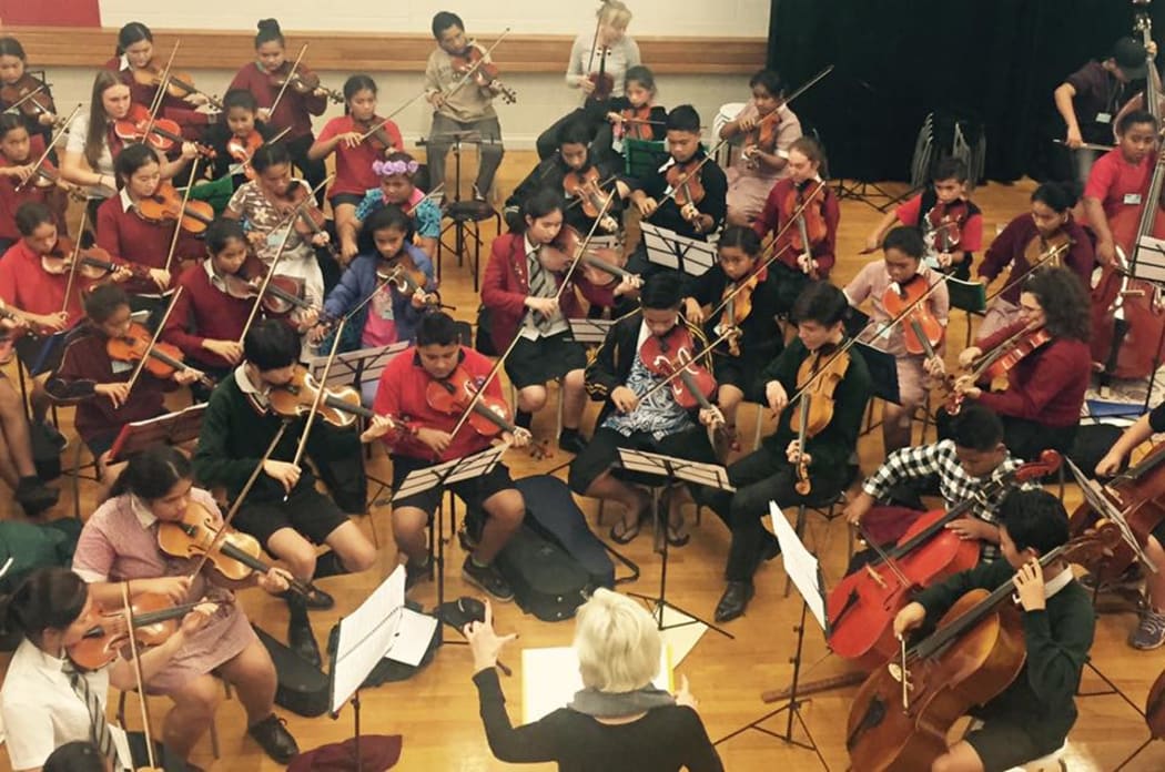 Sistema Music Director Jess Hindin conducting school children