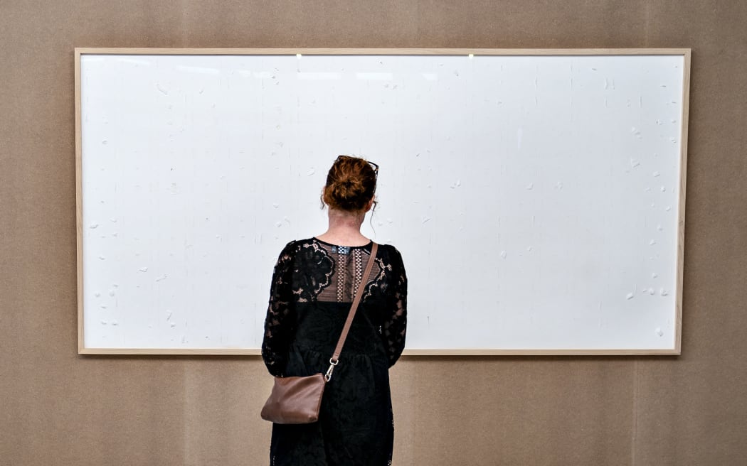 A woman stands in front of an empty frame from Danish artist Jens Haaning in the Kunsten Museum in Aalborg, Denmark.