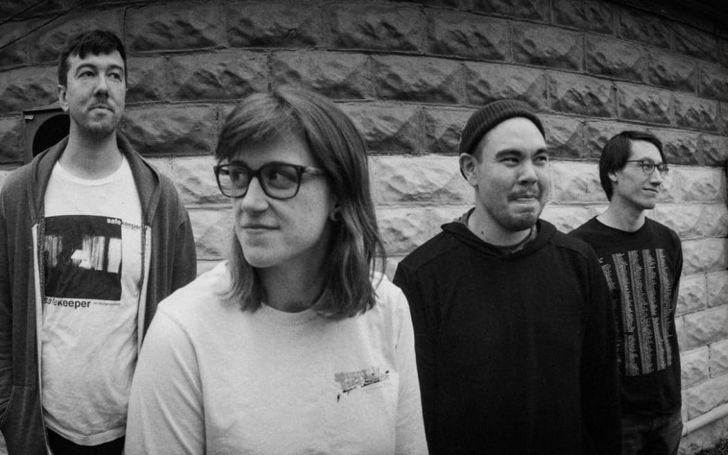Broken Record band members standing in a line infront of a wall
