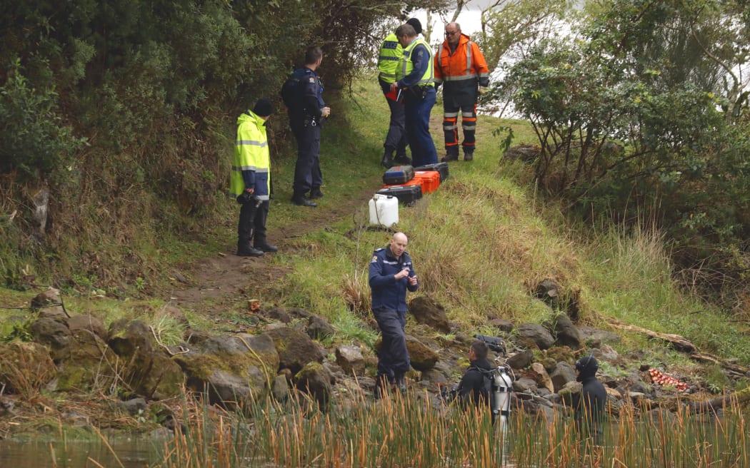 The police dive squad near the shore of Lake Rotoma as they try to recover a car that plunged into the waters.