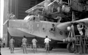 RNZAF ground crew work on Singapore flying boat in Laucala Bay hanger, Fiji.