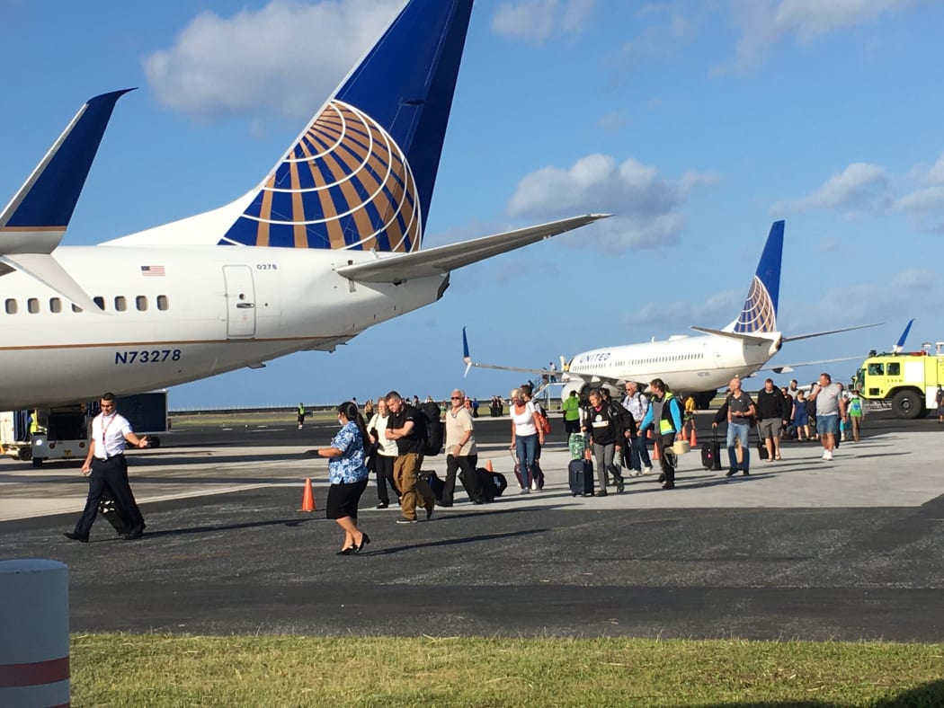 Passengers and crew leave a grounded United Airlines plane (right) after sleeping on the plane to board a "rescue" flight on 19 March