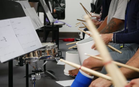 Participants of a music course at Chch men's prison drum on buckets with members of the CSO
