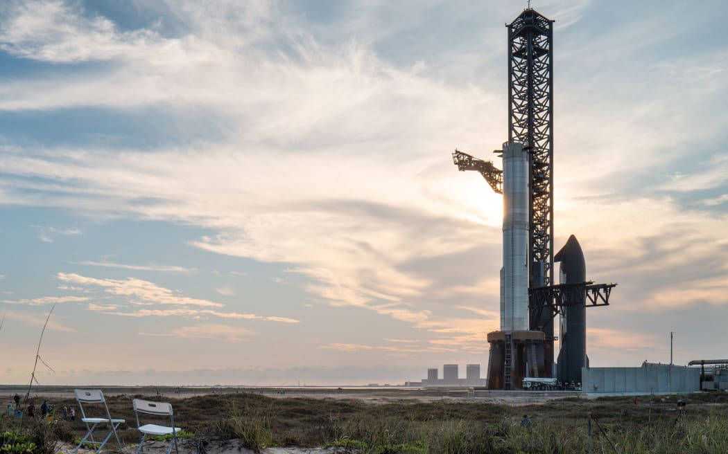 SpaceX Starship, shown sitting to the right of the launch tower beside the Super Heavy booster, is set to lift off on Monday for an integrated test flight of the rocket system.