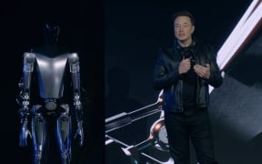 This video screen grab made from Tesla AI Day 2022 livestream shows Elon Musk standing on stage next to Optimus the humanoid robot in Palo Alto, California on September 30, 2022. (Photo by Tesla / AFP) / RESTRICTED TO EDITORIAL USE - MANDATORY CREDIT "AFP PHOTO / HANDOUT / TESLA " - NO MARKETING - NO ADVERTISING CAMPAIGNS - DISTRIBUTED AS A SERVICE TO CLIENTS