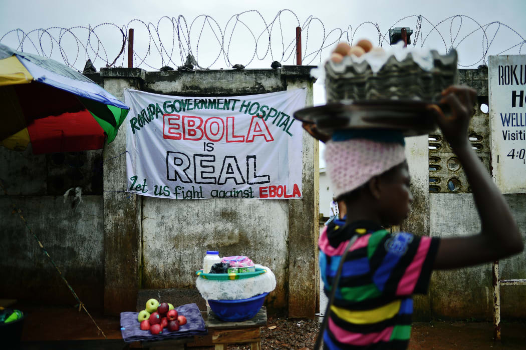 A girl walks past a sign warning of the dangers of Ebola outside a government hospital in Freetown, Sierra Leone, in August 2014.