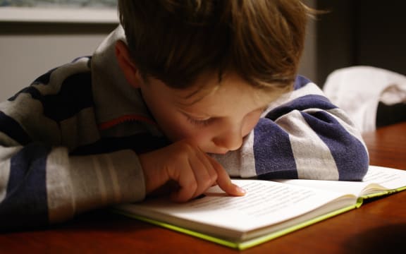 Child reading a book using their finger as a guide