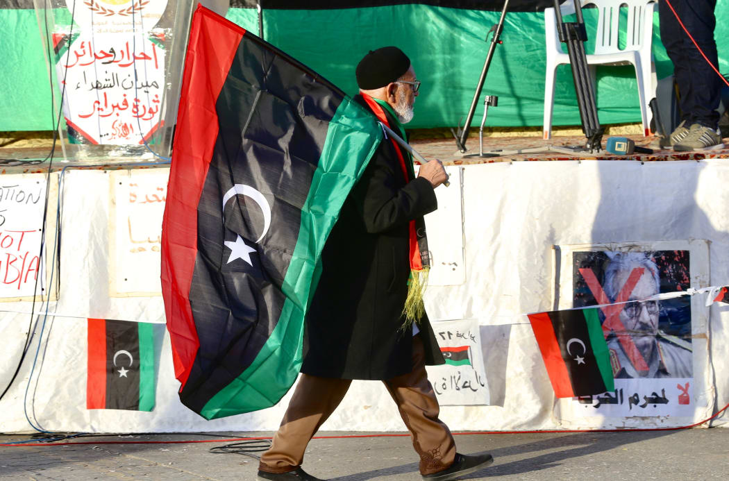 An old man carries a flag of Libya during a protest against the attacks and ceasefire violations in Tripoli on January 24, 2020.