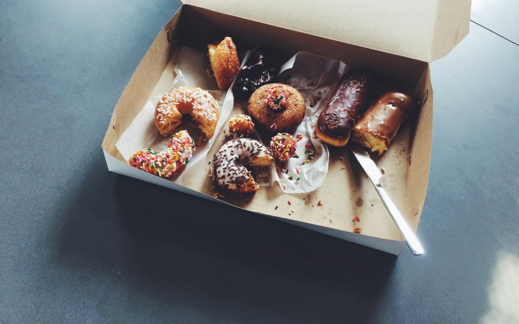 A carton box of half eaten pastries, including doughnuts.
