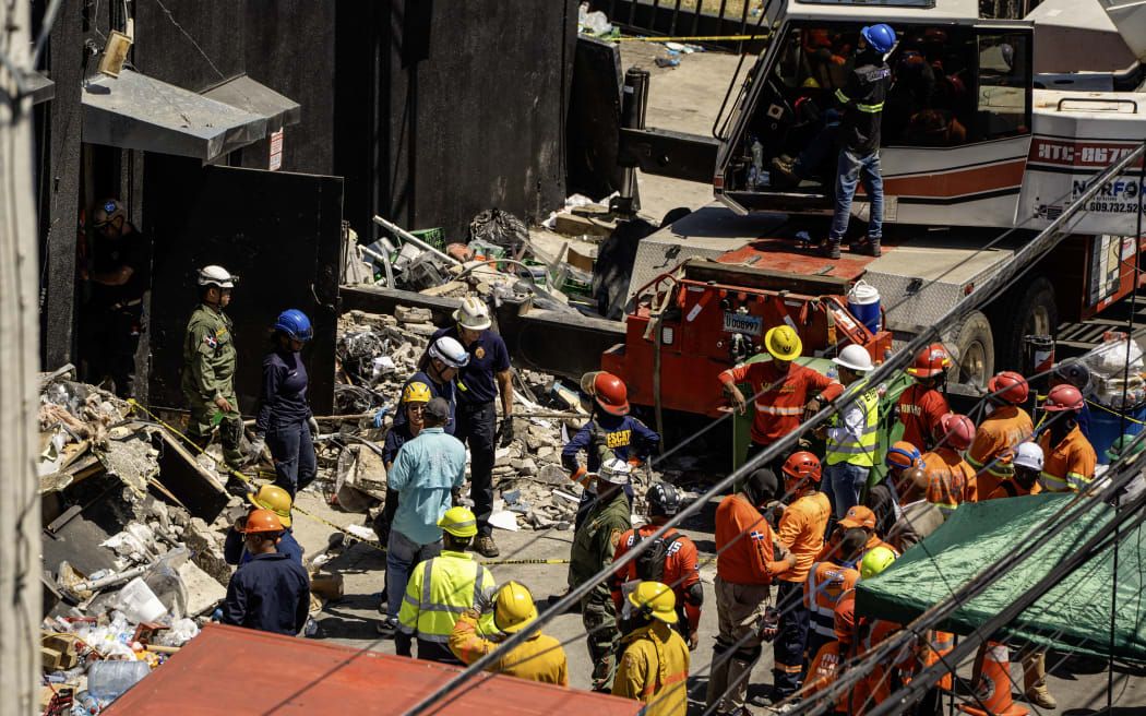 Personnel from civil defense and firefighters work at the Jet Set nightclub following the collapse of its roof in Santo Domingo on April 8, 2025. Rescuers raced to find survivors Tuesday among the rubble of a Dominican Republic night club where at least 44 people died and dozens were hurt in an early-morning roof collapse. (Photo by Francesco SPOTORNO / AFP)