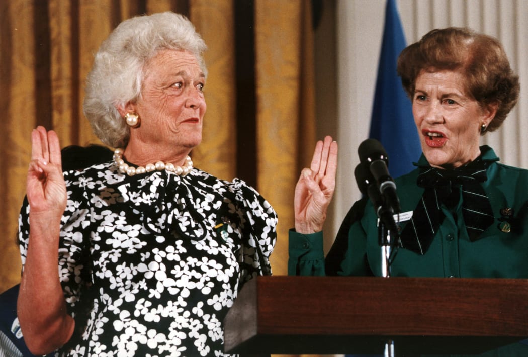First Lady Barbara Bush gives the Girl Scout salute as she is invested as the 14th national honorary president of the Girl Scouts/USA by the organiztion's former national president Betty Pilsbury on 28 June 1989.