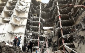 Iranians gather at the site where a 10-storey building collapsed as rescue operations continue in the southwestern city of Abadan.