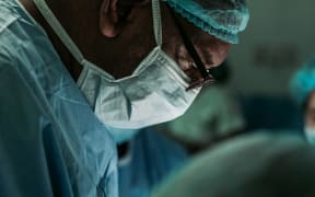 A doctor works on a patient in a surgery.