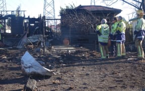 Firefighters survey a destroyed house.