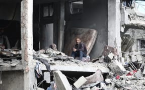 A Palestinian man sits amid the destruction in an apartment building hit in Israeli strikes following his return to Nuseirat in the central Gaza Strip when the bombardment of the camp stopped on November 29, 2024, amid the ongoing war in the Palestinian territory between Israel and Hamas. (Photo by Eyad BABA / AFP)