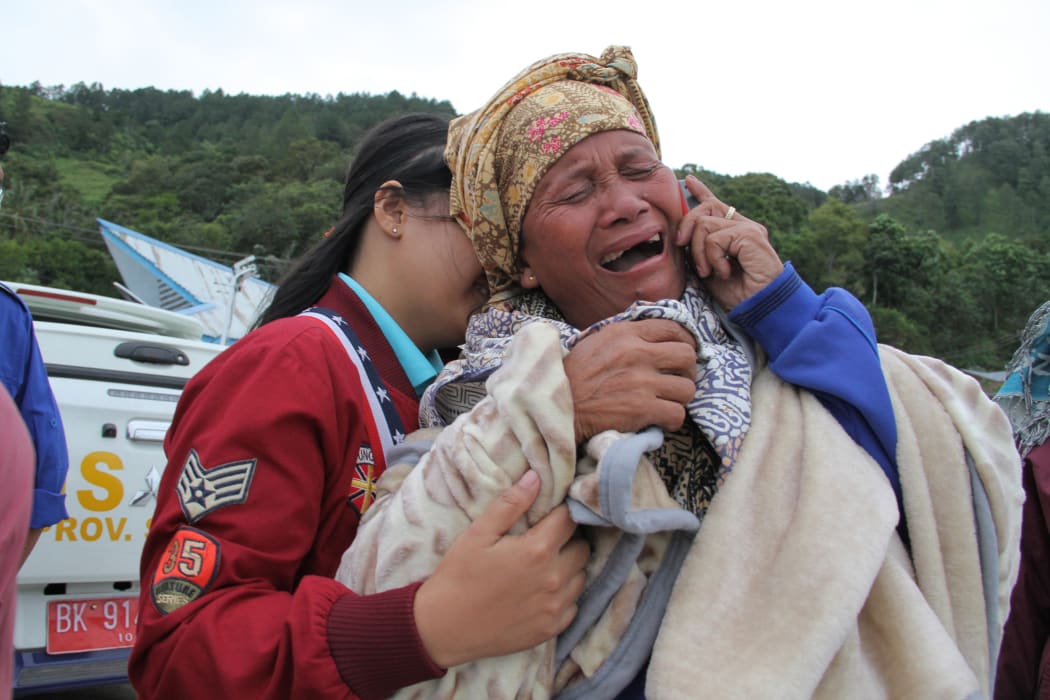A woman cries as she finds out her family are listed as missing, at the Lake Toba ferry port in the province of North Sumatra on June 19, 2018, after a boat capsized the day before.