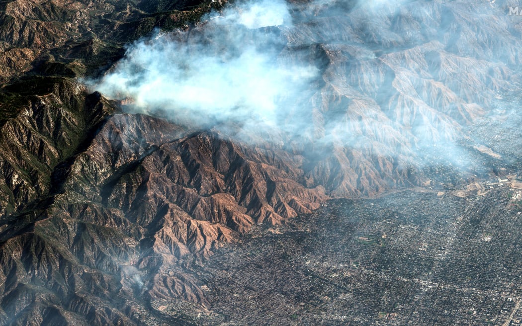 This satellite image taken and released by Maxar Technologies on January 10, 2025 shows smoke as the Eaton Fire continues to burn in Altadena, California. Massive wildfires that engulfed whole neighborhoods and displaced thousands in Los Angeles have killed at least 10 people, authorities said, as California's National Guard soldiers readied to hit the streets to help quell disorder. News of the growing toll, announced late Thursday January 9 by the Los Angeles County Medical Examiner, came as swaths of the United States' second-largest city lay in ruins. (Photo by Satellite image ©2025 Maxar Technologies / AFP) / RESTRICTED TO EDITORIAL USE - MANDATORY CREDIT "AFP PHOTO/ SATELLITE IMAGE ©2025 MAXAR TECHNOLOGIES" - NO MARKETING NO ADVERTISING CAMPAIGNS - DISTRIBUTED AS A SERVICE TO CLIENTS - THE WATERMARK MAY NOT BE REMOVED/CROPPED